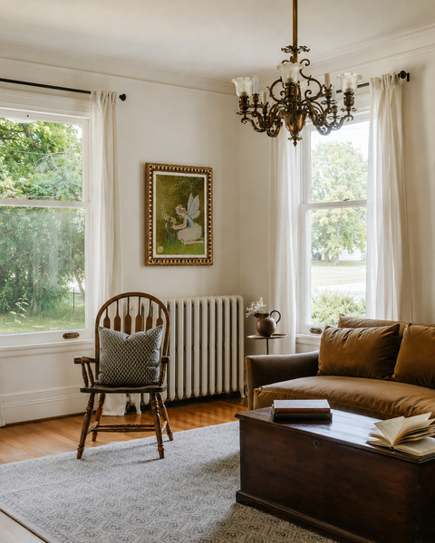 Vintage modern living room with brown leather sofa, charming wooden chair, vintage chandelier, and fairy wall art.