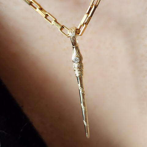 Gold necklace with a unique pendant on a neutral background